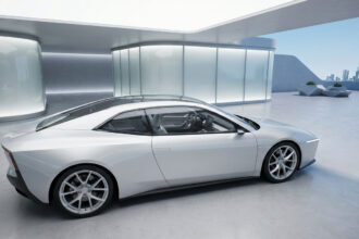 Sleek white futuristic electric sports car with minimalist design in a modern, well-lit architectural setting with city skyline.