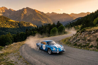Alpine A110 bleue n°17 sur route de montagne sinueuse, levant de la poussière. Coucher de soleil sur les Pyrénées boisées.