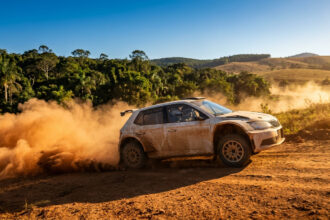 Une voiture de rallye Skoda soulève un épais nuage de poussière sur une piste en terre lors d'une course.
