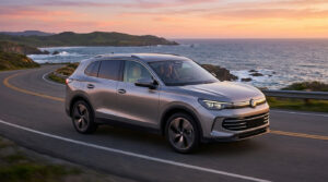 Un SUV Volkswagen argenté roulant sur une route côtière sinueuse au coucher du soleil.